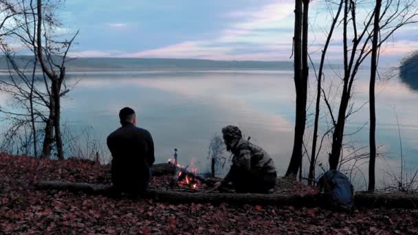 Dos Amigos Sientan Junto Fuego Leña Junto Lago Relajan — Vídeos de Stock