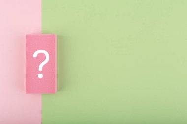 Fotokopi alanı olan pembe ve yeşil arkaplanda beyaz soru işareti. Düz konum, soru ile birlikte en az modayı oluşturan kompozisyon