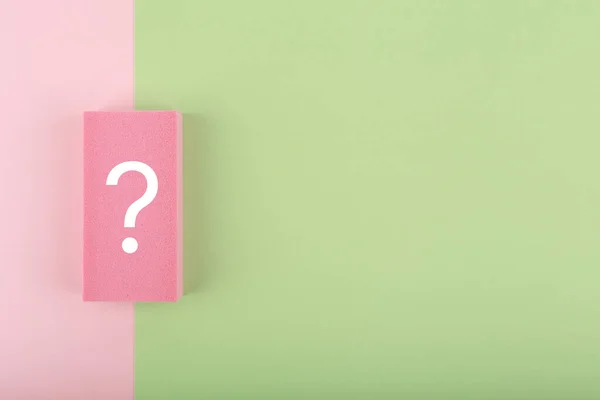 Fotokopi alanı olan pembe ve yeşil arkaplanda beyaz soru işareti. Düz konum, soru ile birlikte en az modayı oluşturan kompozisyon