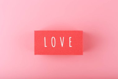 Kırmızı dikdörtgen üzerine yazılmış sözcük sevgisi ile pembe arkaplan arasında kopyalanmış boşluk. Sevgililer Günü 'nün asgari trend konsepti, aşk duyguları, yıldönümü veya flört.