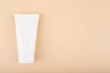 Krem, merhem, maske, bej arka planda fotokopi alanı olan beyaz plastik kozmetik tüp. Manikür, el ve yüz için doğal organik cilt bakım ürünleri kavramı