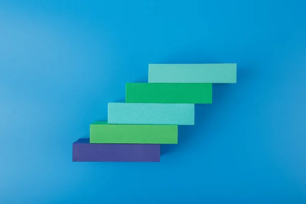 Concepto de desarrollo empresarial. Escalera de rectángulos multicolores con espacio para texto sobre fondo azul — Foto de Stock