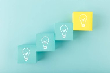 Fikir kavramı, yaratıcılık, başlat ya da beyin fırtınası yap. Oyuncak küplere çizilmiş beyaz ampuller mavi arka planda bir merdiven gibi