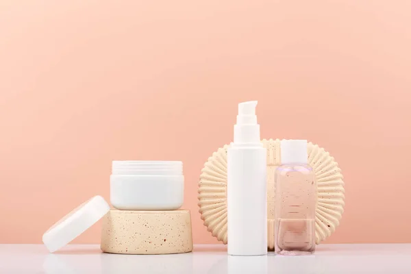 Set of skin care products on gypsum shapes on white table against bright beige background with copy space. Products for daily skin care routine and luxury skin treatment