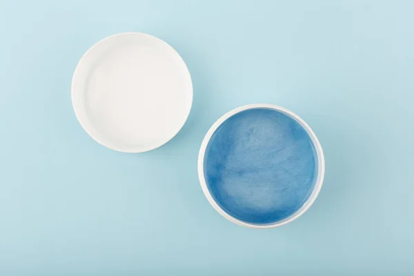 Minimal flat lay with opened jar with blue face or hair mask with sea minerals on light blue background Stock Snímky