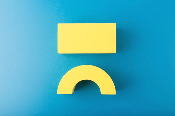 Close up of unhappy or angry yellow smile symbol on blue background. Emotions or emoji concept Stock Obrázky