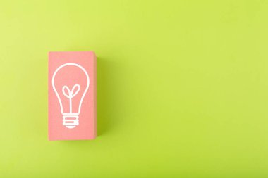 Creativity, innovation and idea concept. Light bulb drawn on pink rectangle on bright green background with copy space