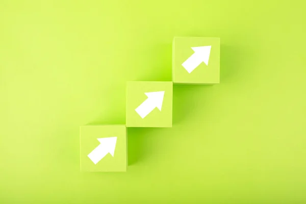 Ladder career, sales or business growth path concept. Green toy cubes as step stairs with white arrows up Stock Snímky