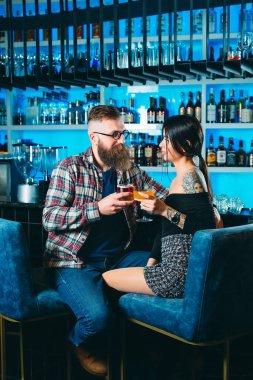 A young couple drinks cocktails at the bar in a restaurant