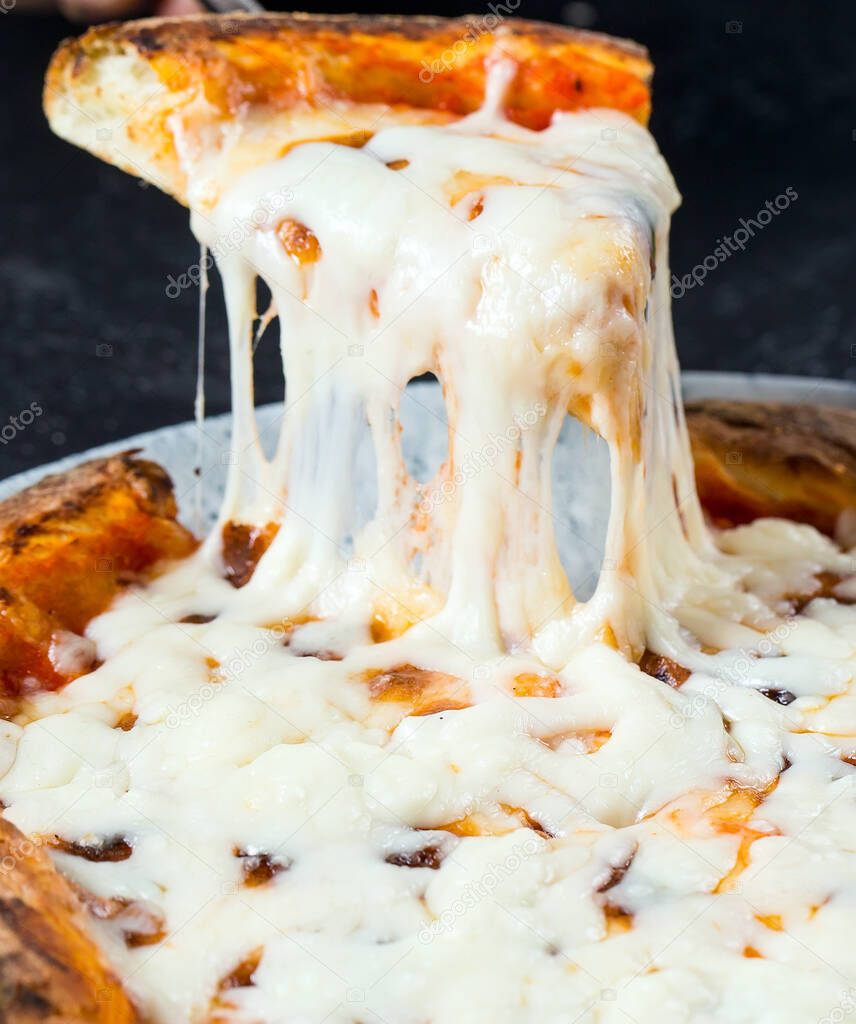 Tasty take slice of pizza with cheese. Appetizing separate piece of round pizza stretching melted cheese