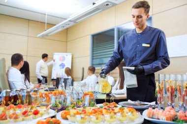 Genç bir garson yemek servisi için içki dolduruyor.