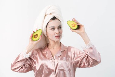 Yüz bakımı ve güzellik tedavileri. Yüzünde nemlendirici avokado maskesi olan bir kadın beyaz arka planda izole edilmiş.