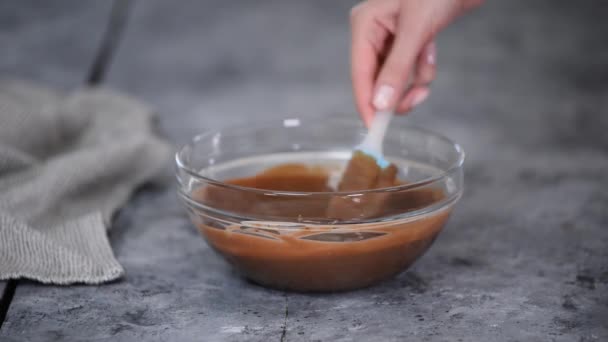 Mulher confeiteiro misturando molho de chocolate em uma tigela de vidro. — Vídeo de Stock