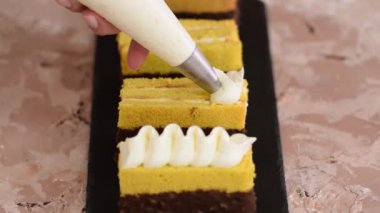 Kadın eli, sünger keki bir pasta torbasından çıkan kremayla süslüyor..