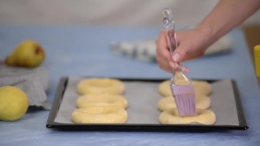 Çiğ çörekler yumurta ile yağlanır ve pişirmeye hazırlanır..