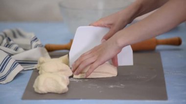 Bir kadın masadaki hamuru keser. Mayalı çörek yapıyorum..