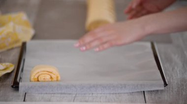 Raw sweet yeast dough on a baking sheet, filling buns jam. Preparation for baking.