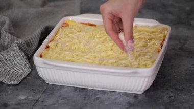 Aşçı İtalyan lazanyası pişiriyor, üstüne mozzarella serpiştiriyor..