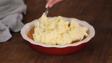 Kadın çoban turtası yapıyor. Patates püresi kıymanın üstüne konuyor..