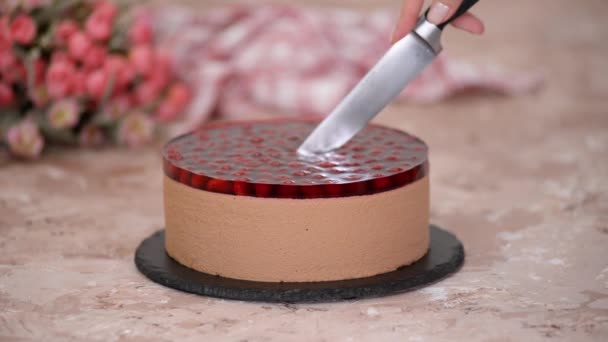 Cutting chocolate mousse cake with cherries jelly. — Stock Video