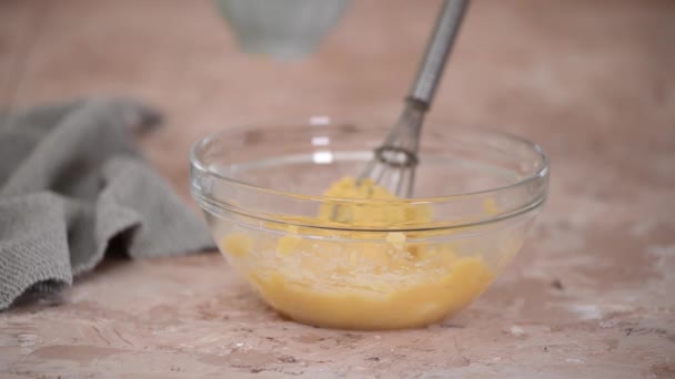 Preparación de masa de choux en un tazón de vidrio. Añadir huevos a la masa. — Vídeo de stock