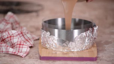 Genç kadın pasta şefi bir kalıba sıvı köpük döküyor..