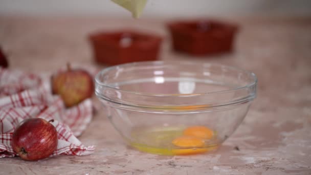 Jovem mulher fazendo massa na cozinha. Ovos batidos com açúcar em uma tigela. — Vídeo de Stock