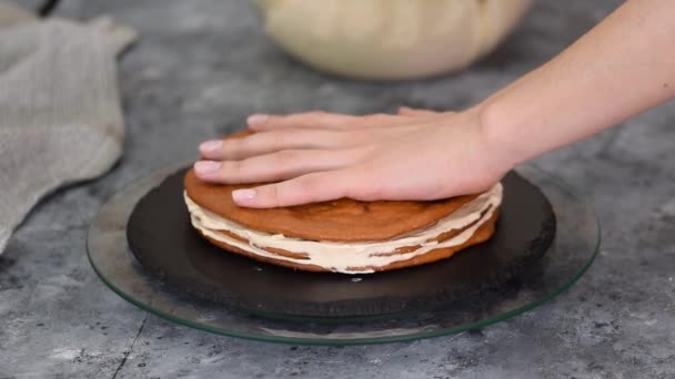 Μπέικερ ζαχαροπλαστικής smoothies ένα στρώμα κρέμας καραμέλας σε ένα στρώμα κέικ με μια σπάτουλα. — Αρχείο Βίντεο