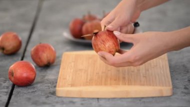 Close-up of hands peeling an apple. Womans hands removes the skin of a red apple with a knife