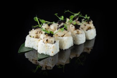 Siyah bir arka planda yansımalı geleneksel lezzetli suşi rulosu. Pilavlı suşi, nori, krem peynir, tobiko havyarı, avokado. Suşi menüsü. Japon mutfağı, restoran. Asya yemekleri