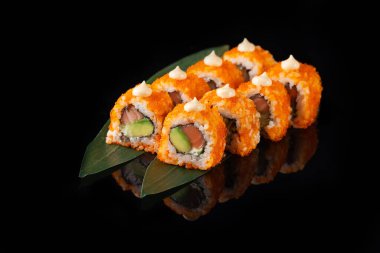 Siyah bir arka planda yansımalı geleneksel lezzetli suşi rulosu. Pilavlı suşi, nori, krem peynir, tobiko havyarı, avokado. Suşi menüsü. Japon mutfağı, restoran. Asya yemekleri