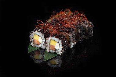 Siyah bir arka planda yansımalı geleneksel lezzetli suşi rulosu. Pilavlı suşi, nori, krem peynir, tobiko havyarı, avokado. Suşi menüsü. Japon mutfağı, restoran. Asya yemekleri