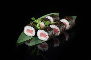 Siyah bir arka planda yansımalı geleneksel lezzetli suşi rulosu. Pilavlı suşi, nori, krem peynir, tobiko havyarı, avokado. Suşi menüsü. Japon mutfağı, restoran. Asya yemekleri