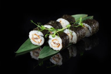 Siyah bir arka planda yansımalı geleneksel lezzetli suşi rulosu. Pilavlı suşi, nori, krem peynir, tobiko havyarı, avokado. Suşi menüsü. Japon mutfağı, restoran. Asya yemekleri