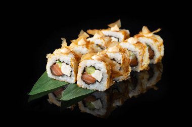 Siyah bir arka planda yansımalı geleneksel lezzetli suşi rulosu. Pilavlı suşi, nori, krem peynir, tobiko havyarı, avokado. Suşi menüsü. Japon mutfağı, restoran. Asya yemekleri