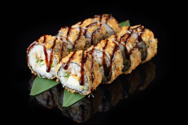 Siyah arkaplanda yansımalı sıcak tempura dönüşü. Pilavlı suşi, nori, krem peynir, yılan balığı, avokado. Suşi menüsü. Japon mutfağı, restoran. Asya yemekleri
