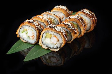 Siyah bir arka planda yansımalı geleneksel lezzetli suşi rulosu. Pilavlı suşi, nori, krem peynir, tobiko havyarı, avokado. Suşi menüsü. JHot tempura sarması. Asya yemekleri