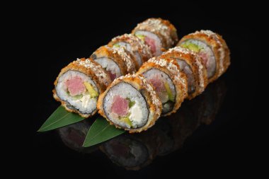 Siyah bir arka planda yansımalı geleneksel lezzetli suşi rulosu. Pilavlı suşi, nori, krem peynir, tobiko havyarı, avokado. Suşi menüsü. Japon mutfağı. Sıcak tempura.