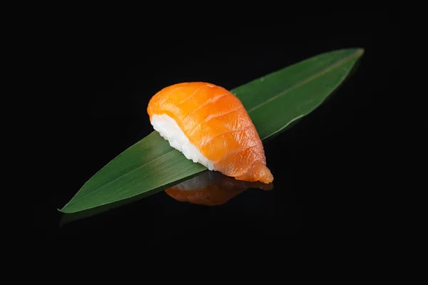 Eating sushi. Delicious Japanese cuisine. Traditional delicious fresh nigiri sushi with salmon on a black background with reflection. Sushi menu. Japanese kitchen, restaurant. Asian food