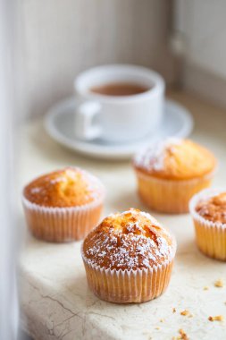 Pudra şekerli ve çiçekli tatlı kekler. Ev yapımı fırın. Meyve ağacı çiçekleriyle süslenmiş beyaz kapsüllü çörekler. Bahar Fırını.