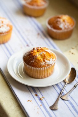 Pudra şekerli ve çiçekli tatlı kekler. Ev yapımı fırın. Meyve ağacı çiçekleriyle süslenmiş beyaz kapsüllü çörekler. Bahar Fırını.