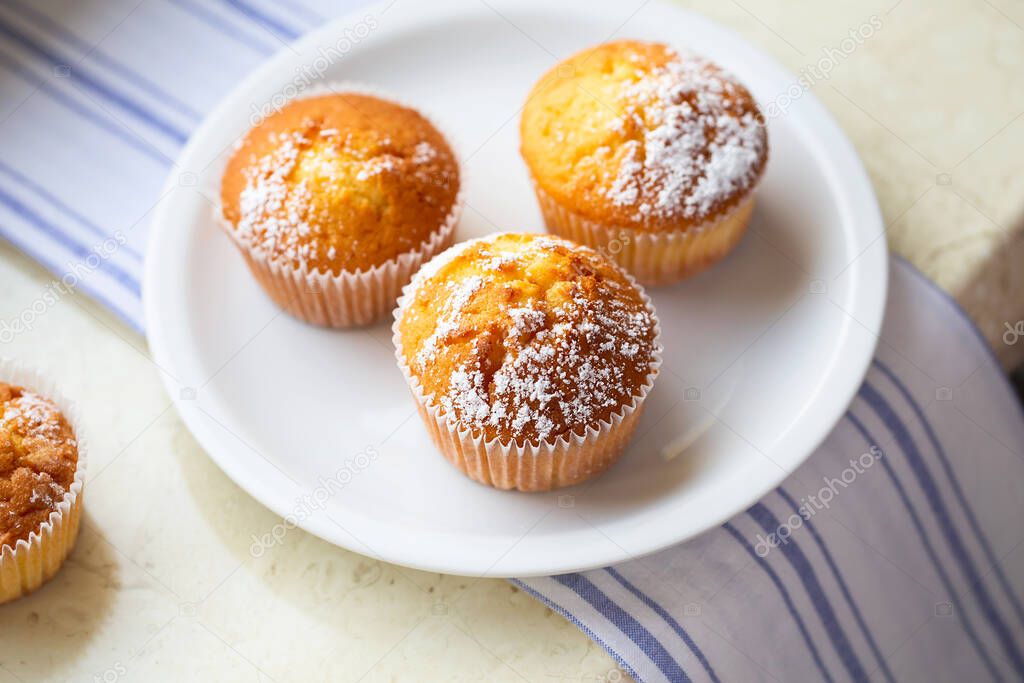 Sweet muffins with powdered sugar and blossoms. Homemade bakery. Muffins in white capsules decorated with fruit tree flowers. Spring time bakery.