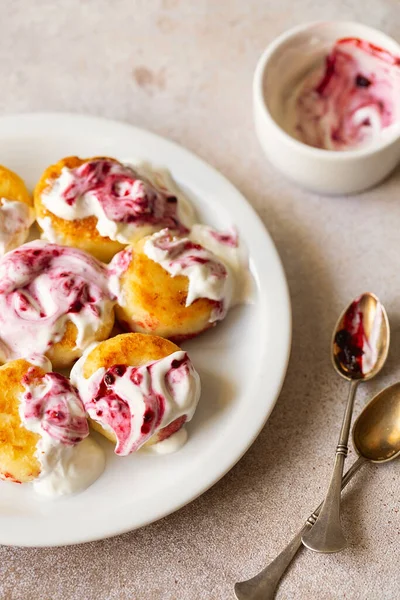 Süzme peynirli krep, şurup, ekşi krema ve reçelli seramik tabakta ricotta böreği. Sağlıklı ve lezzetli bir sabah kahvaltısı. Bej arka plan. Çocuklar için yemek. Ukrayna mutfağı.