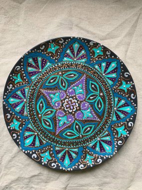 Decorative ceramic plate with  different colors. painted plate on white background, closeup, top view. Decorative porcelain plate painted with acrylic paints, handwork, dot painting