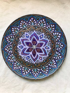 Decorative ceramic plate with  different colors. painted plate on white background, closeup, top view. Decorative porcelain plate painted with acrylic paints, handwork, dot painting
