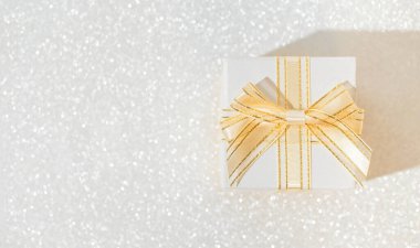 Pırıl pırıl arka planı olan beyaz hediye kutusu. Noel ya da doğum günü hediyesi. Kutlama konsepti. Üst Manzara. Düz yatıyordu
