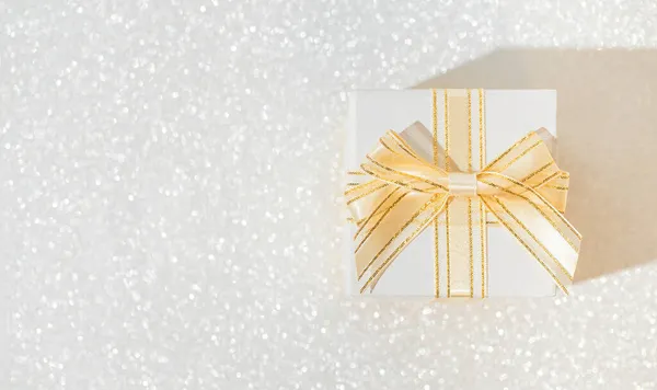 Pırıl pırıl arka planı olan beyaz hediye kutusu. Noel ya da doğum günü hediyesi. Kutlama konsepti. Üst Manzara. Düz yatıyordu