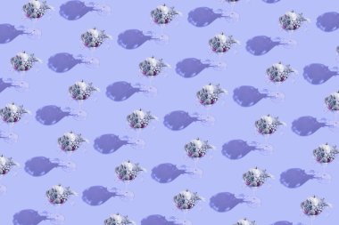 Gümüş süs eşyalarıyla martini bardağından yapılmış yaratıcı desen ve pastel leylak arka planda fiyonklar. Parti ve festival konsepti. Noel kutlaması teması. Asgari biçim