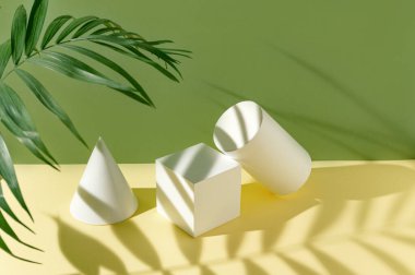 Beyaz geometrik figürlerden oluşan soyut kompozisyon palmiye yaprağı ve yeşil ve sarı pastel renkli arka planda gölgeler. Asgari biçim