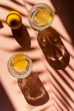 İki bardak su ya da arka planda gölgeli dilimlenmiş limonlu limonata. Yaz tatili konsepti. Asgari düzeyde. Üst görünüm.